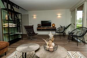 a living room filled with furniture and a tv at Luxe Vakantiehuis Zeeland in Wilhelminadorp