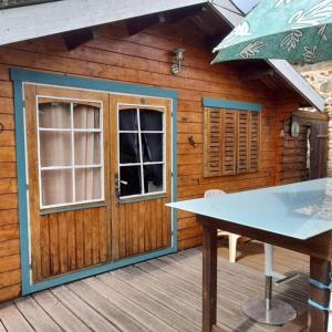 a wooden cabin with a table and an umbrella at Chalet en bois en pleine Nature 4 personnes 3 lits Aventure Bien être et NAture Ferme Peyrot 64 in Vielleségure