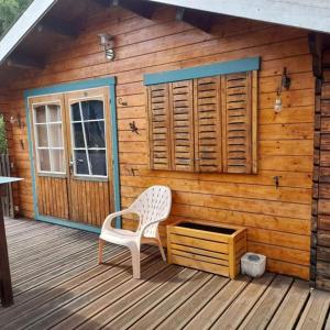 a wooden cabin with a white chair on a deck at Chalet en bois en pleine Nature 4 personnes 3 lits Aventure Bien être et NAture Ferme Peyrot 64 in Vielleségure