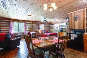 a dining room with a table and a living room at Historic Log Cabin with Porch Near Patoka Lake! in Taswell