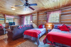 a log cabin bedroom with two beds and a ceiling fan at Historic Log Cabin with Porch Near Patoka Lake! in Taswell
