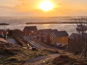 un grupo de casas con la puesta de sol en el fondo en Rorbu ved sjøen, en Bud