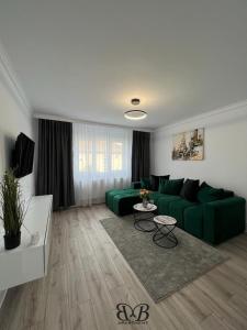 a living room with a green couch and a table at B&B Apartment in Oţelu Roşu