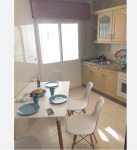 eine Küche mit einem weißen Tisch und Stühlen sowie einem Tisch und einem Chairsktop in der Unterkunft Cómodo piso en Camino Inglés (a 10 min de Santiago) in Sigüeiro