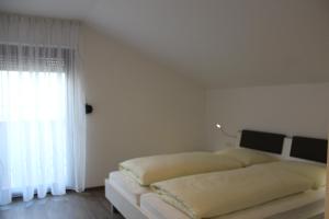 a white bedroom with a bed and a window at Pension Georgenhof in Cermes