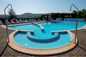 a large blue swimming pool with chairs in it at Hillside Apartman in Dunaszentmiklós