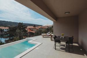 un patio con piscina, tavolo e sedie di SOL luxury residence near the beach with shared heated pool a Božava