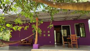 Casas Guanacaste Marbella في Marbella: منزل أرجواني مع كراسي وأرجوحة في الخارج