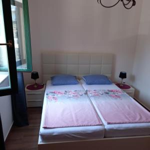 Schlafzimmer mit einem Bett mit rosa Bettwäsche und blauen Kissen in der Unterkunft Apartman Doris in Krasići