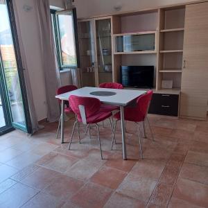ein Esszimmer mit einem Tisch und roten Stühlen in der Unterkunft Apartman Doris in Krasići