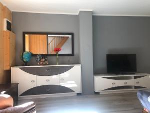 a living room with a television and a white cabinet at Au Cœur des montagnes in La Chalp