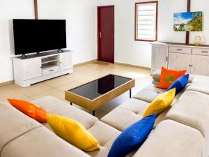 uma sala de estar com um sofá com almofadas coloridas em Villa exotique em Le Moule