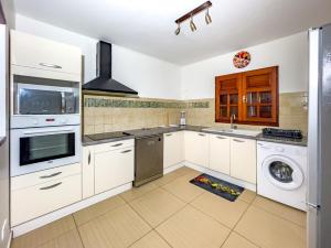 uma cozinha com armários brancos e uma máquina de lavar e secar roupa em Villa exotique em Le Moule