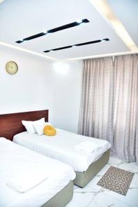 2 łóżka w pokoju z białymi ścianami w obiekcie Stylish 3-bedroom condo with a Power-backup, Swimming pool and Gym w mieście Kampala