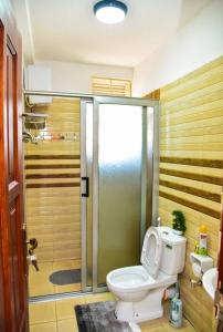 a bathroom with a toilet and a shower with a shower at Stylish 3-bedroom condo with a Power-backup, Swimming pool and Gym in Kampala