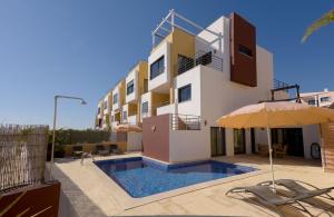 a building with a swimming pool and an umbrella at Vila Vida in Ferragudo