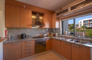 a kitchen with wooden cabinets and a large window at Vila Vida in Ferragudo