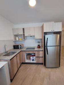 a kitchen with a stainless steel refrigerator and wooden cabinets at Departamento confortable en Quito in Quito