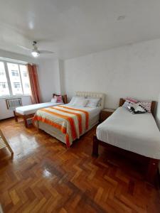 a bedroom with two beds and a wooden floor at Apartamento Copacabana vista lateral mar in Rio de Janeiro