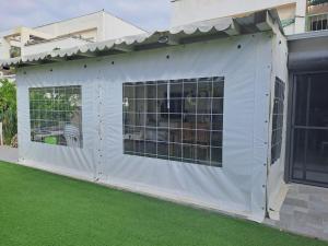 a white garage with windows and green grass at סטודיו במרכז מודיעין in Modi'in