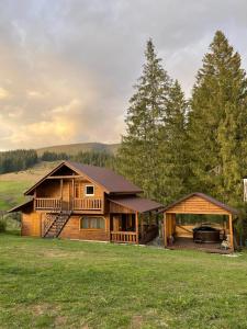 ein Blockhaus mit einer Veranda und einem Haus in der Unterkunft На горі in Worochta