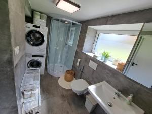 a bathroom with a sink toilet and a washing machine at Veselá lama U nás doma in Baška