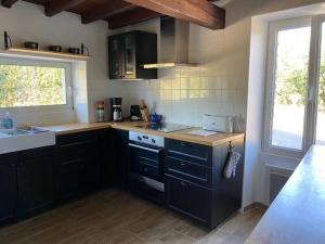 cocina con armarios negros, fregadero y ventana en Maison proche de la mer 110m2, en Glatigny