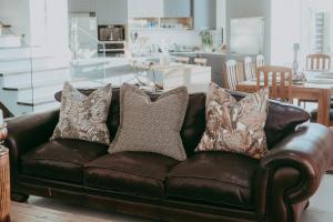 a brown leather couch with pillows in a living room at Oceana View Selfcatering Accommodation in Rand Rifles