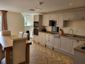 a kitchen with white cabinets and a wooden table at The Hideaway in Chapel en le Frith