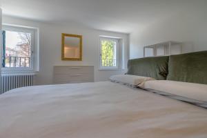 ein weißes Schlafzimmer mit einem großen Bett und zwei Fenstern in der Unterkunft A CASA DI LUPO in Cison di Valmarino