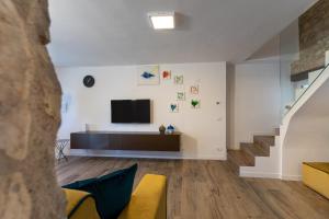 ein Wohnzimmer mit einem TV und einer Treppe in der Unterkunft A CASA DI LUPO in Cison di Valmarino