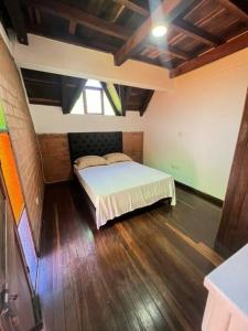 een slaapkamer met een bed in een kamer met houten vloeren bij Casa en envigado ubicación perfecta para disfrutar de la naturaleza y la ciudad in Envigado