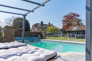 uma piscina com um guarda-sol ao lado de uma casa em Craythornes by Bloom Stays em New Romney
