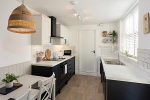a kitchen with white cabinets and a sink and a table at Low Tide @ Filey. Close to Beach. Dog Friendly. in Filey
