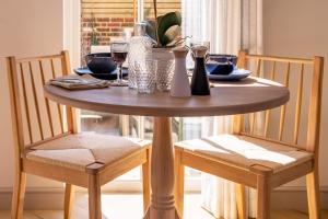 uma mesa de madeira com 2 cadeiras e uma mesa com copos de vinho em The Nook em Burley