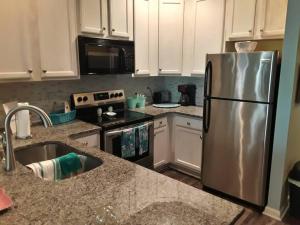 a kitchen with a stainless steel refrigerator and white cabinets at Legends Golf Beachy Condo in Myrtle Beach