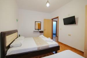 een slaapkamer met een bed en een tv aan de muur bij Apartments & Hotel Eleanna in Sarandë