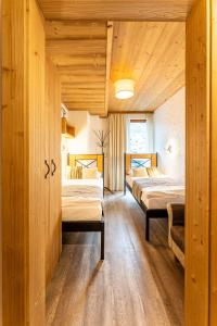 two beds in a room with wooden walls at Apartmán SAFFRON Chalet JASNÁ in Demanovska Dolina