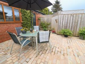 a patio with a table and chairs and an umbrella at Kilmory Lodge in Poulton le Fylde