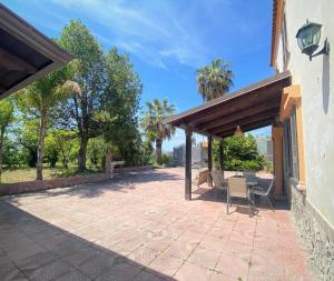 een patio met een tafel en stoelen en palmbomen bij Suite 24 Ercolano in Ercolano