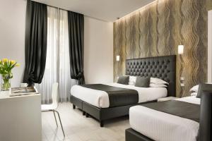 ローマにあるホテル パトリアのベッド2台とテーブルが備わるホテルルームです。