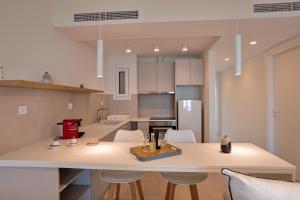 a kitchen with a large white counter and chairs at La Mer Bleue Beachfront Boutique Apartments in Vrahati