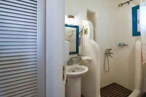 La salle de bains blanche est pourvue d'un lavabo et d'un miroir. dans l'établissement Triantaros Artful Houses, à Triandáros