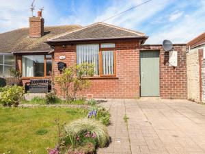 a brick house with a door and a yard at Bungalow by the Sea in Cleveleys