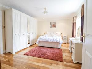 een witte slaapkamer met een bed en een rood tapijt bij 1 The Beeches in Llangollen
