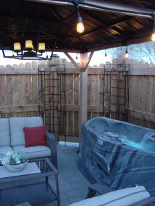 a hot tub on a patio with a couch and a table at Prairie Rose Cottage in Fort Macleod