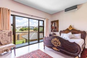 a bedroom with a large bed and a balcony at Pearl House in Centurion