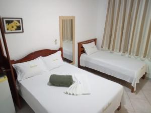 two beds in a room with white walls at Pousada Santos in Parintins