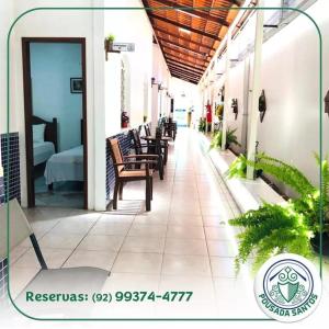un couloir d'un hôtel avec des tables et des chaises dans l'établissement Pousada Santos, à Parintins