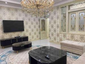 uma sala de estar com uma televisão e um lustre em Luxury huge Apartment em Tashkent